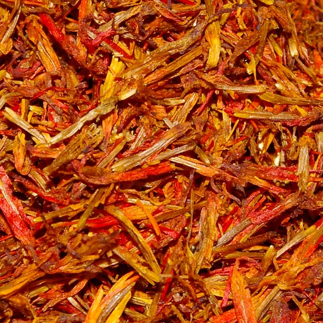 A dense close-up of dried saffron threads showing red, orange, and amber strands.