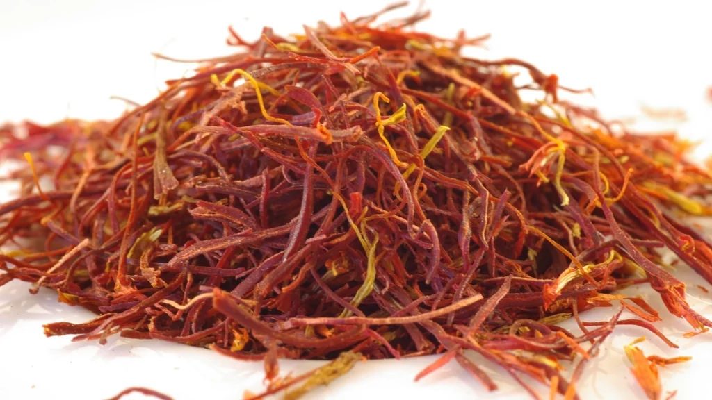 A mound of loose saffron threads spread across a pale surface in close-up.